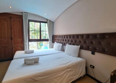 Bedroom with two beds, a window, and wooden wardrobe