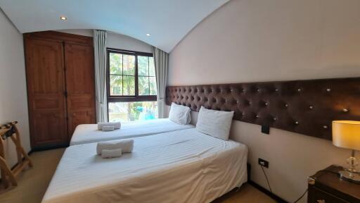 Bedroom with two beds, a window, and wooden wardrobe