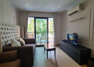 Living room with sofa, TV, coffee table, and balcony access