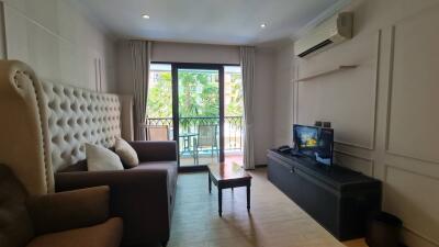 Living room with sofa, TV, coffee table, and balcony access