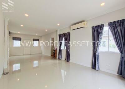 Spacious and well-lit living room with large windows, air conditioning, and tiled flooring.