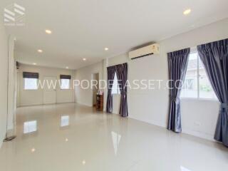 Spacious and well-lit living room with large windows, air conditioning, and tiled flooring.