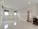 Spacious white-walled living room with small shelving unit and doorway to another room