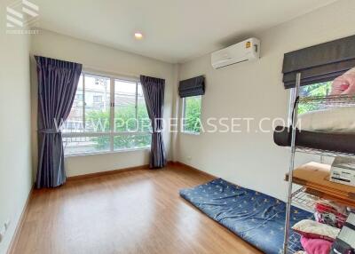 Bright and airy bedroom with large window, wooden flooring, and air conditioning.