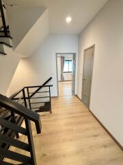 Modern hallway with wooden flooring and metal staircase