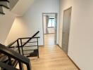 Modern hallway with wooden flooring and metal staircase