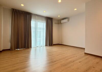 Spacious living room with wooden flooring, large window, and ceiling lights