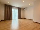 Spacious living room with wooden flooring, large window, and ceiling lights