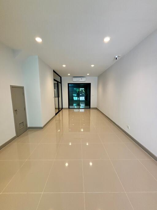 Spacious main living area with tiled floor, recessed lighting, and glass door