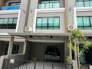 Exterior view of a modern townhouse building with balconies and a gated entrance.