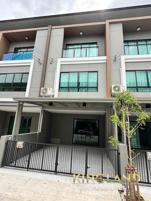 Exterior view of a modern townhouse building with balconies and a gated entrance.