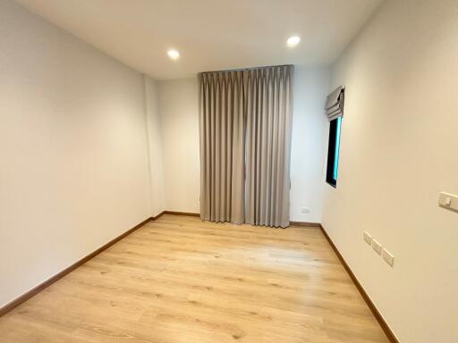 Empty bedroom with wooden floors and curtains