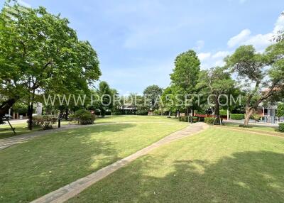 Spacious grassy park area with trees and path