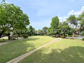 Spacious grassy park area with trees and path