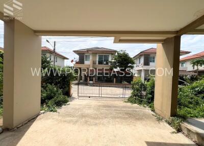 View from the entrance driveway of a gated residential property with neighboring houses visible in the background