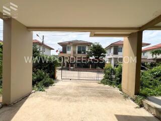 View from the entrance driveway of a gated residential property with neighboring houses visible in the background