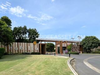 Entrance of a residential complex with well-maintained landscaping and clear skies