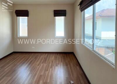 Spacious bedroom with wooden flooring and two windows