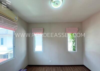 Bright bedroom with two windows and wooden flooring