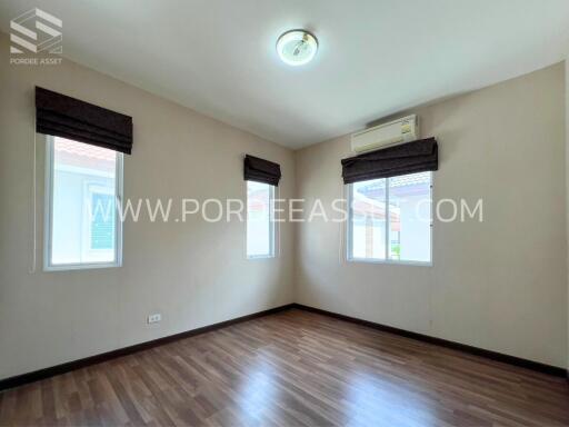 Empty bedroom with wooden floor, windows, and air conditioning