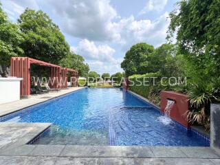 Outdoor swimming pool with water features and surrounding greenery