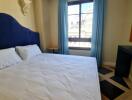 Well-lit bedroom with a large bed, window, and a desk