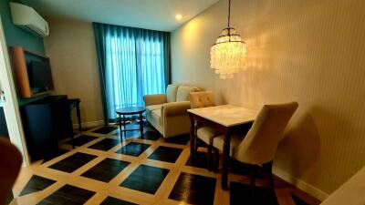 Living room with sofa, dining table, chandelier, and large window