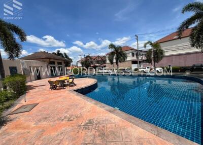 Outdoor pool area with seating and surrounding houses