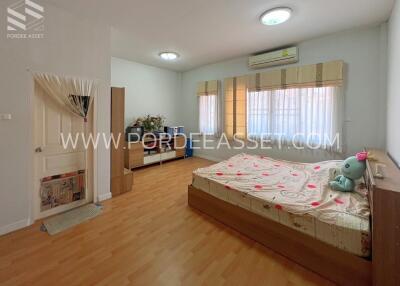 A spacious bedroom with wooden flooring, a large bed, and ample natural light