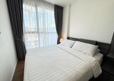 Modern bedroom with a large bed and floor-to-ceiling window with white curtains