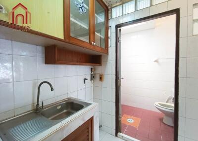 Small kitchen with sink and storage alongside bathroom