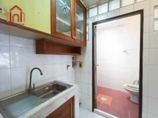 Small kitchen with sink and storage alongside bathroom