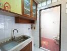 Small kitchen with sink and storage alongside bathroom