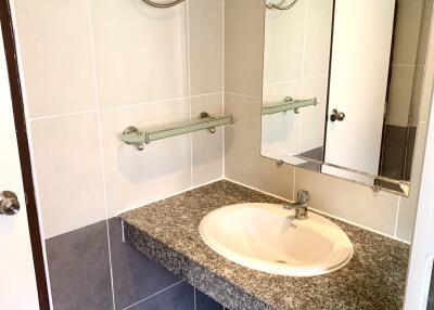 Bathroom with sink, countertop, mirror, and tiled walls