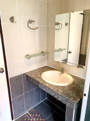 Bathroom with sink, countertop, mirror, and tiled walls