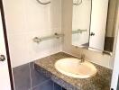 Bathroom with sink, countertop, mirror, and tiled walls