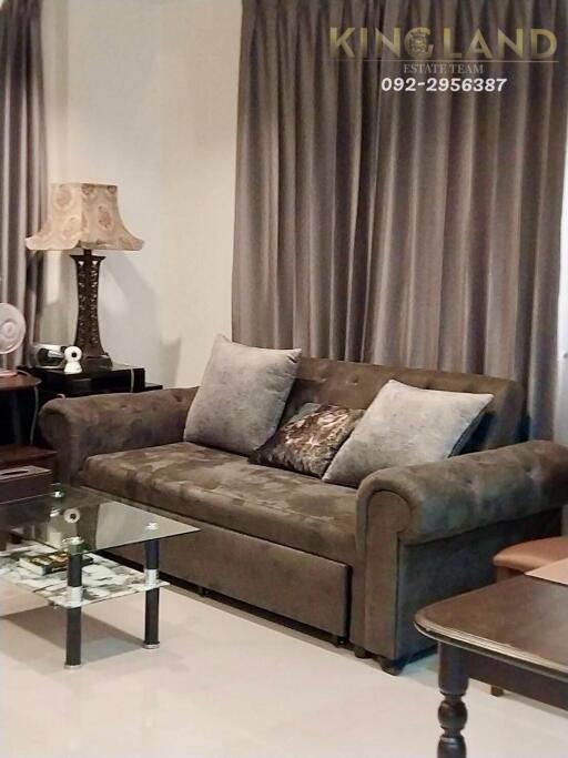 A well-furnished living room with a sofa, a glass coffee table, and various decorative items