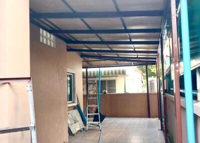 Covered outdoor patio area with tiled floor and ladder