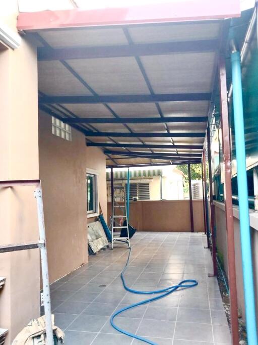 Covered outdoor patio area with tiled floor and ladder