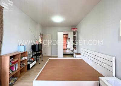 Spacious bedroom with wooden floor, white bed frame, wardrobe and a TV