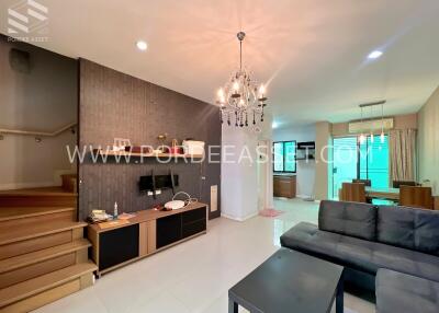 Contemporary styled living room with a staircase, television, and chandelier.