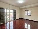 Spacious living room with large windows and polished wooden floor