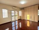 Spacious bedroom with wooden floor and large windows