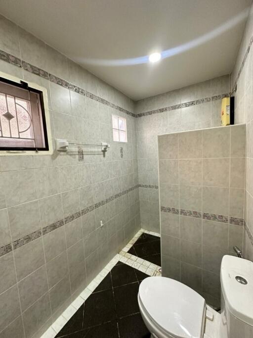 Bathroom with tiled walls, ceiling light, and small windows