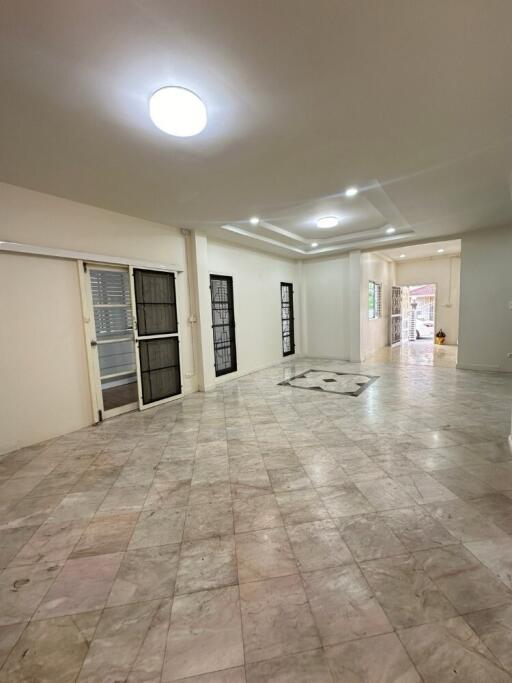 Spacious living room with tiled floor and large windows.