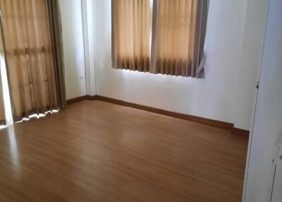 Bright bedroom with wooden flooring and curtains on the windows