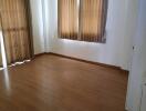 Bright bedroom with wooden flooring and curtains on the windows