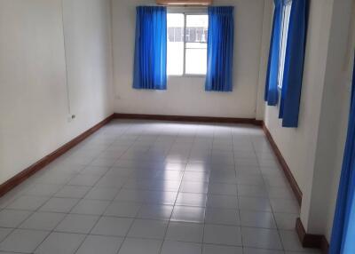 Spacious bedroom with tiled flooring and blue curtains