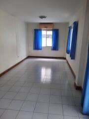 Spacious bedroom with tiled flooring and blue curtains