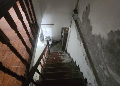 View of staircase leading to lower level with visible damage on walls and steps